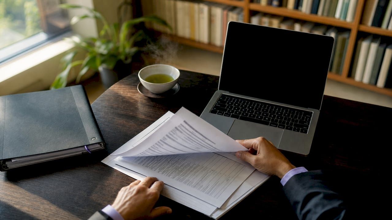 Des mains s'affairent à calculer la rentabilité locative sur un bureau.