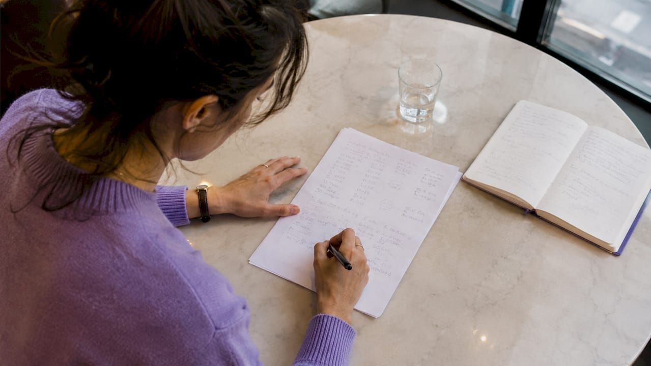 Des mains en train de noter des calculs liés à la taxe foncière sur une feuille.