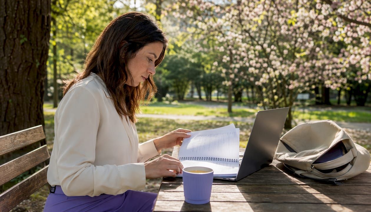 Une femme installée dans un café, en train de rédiger des notes sur la création d'une SCI.