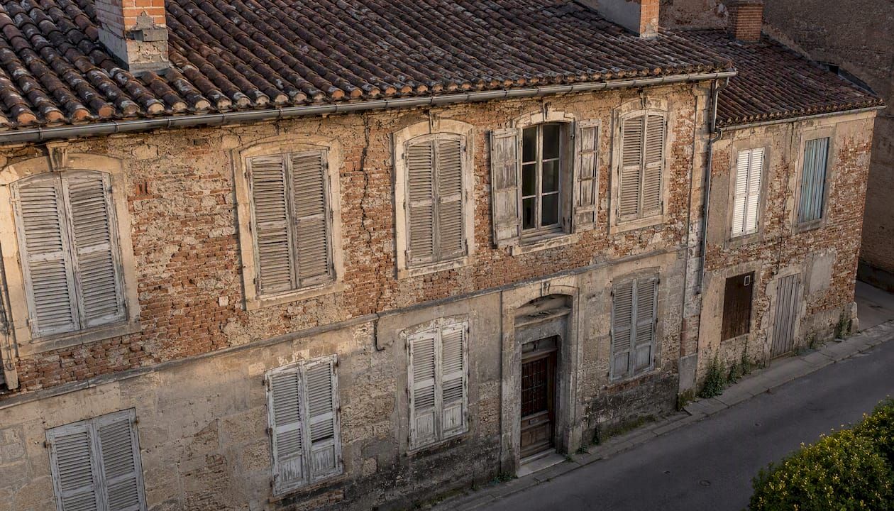 Façade d’un immeuble ancien, marquée par les traces du temps et le charme de ses matériaux patinés.